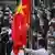 Des Ouïghours assistent à la montée du drapeau chinois.