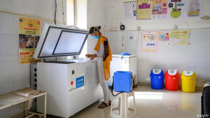 A health worker storing vaccines in a solar-powered refrigeration unit