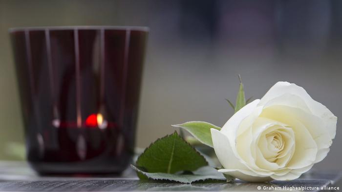 Foto de una vela y una flor en símbolo de luto en una imagen de archivo