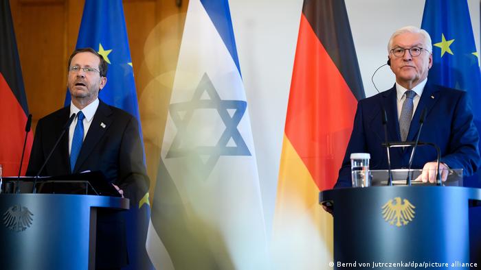 Izchak Herzog und Frank-Walter Steinmeier an Rednerpulten vor den Flaggen Israels, Deutschlands und der EU