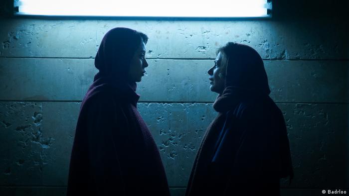 Film stills from the film Without Her by Iranian filmmaker Arian Vazirdaftari;  two women face each other in the shadowy light.