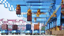 ARCHIV - 04.06.2021, China, Qingdao: Portalkräne bewegen Container auf Transporter in einem Hafen in Qingdao in der ostchinesischen Provinz Shandong. (zu dpa Chinas Außenhandel erleidet unerwarteten Dämpfer) Foto: Uncredited/CHINATOPIX/dpa +++ dpa-Bildfunk +++