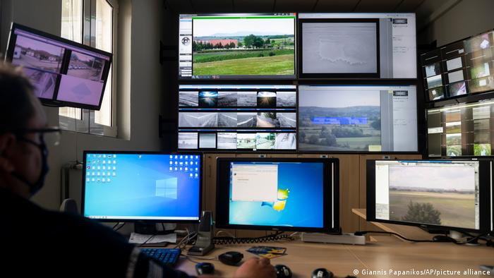 Zdjęcie przedstawia strażnika w centrum monitoringu granicy oraz wiele monitorów
