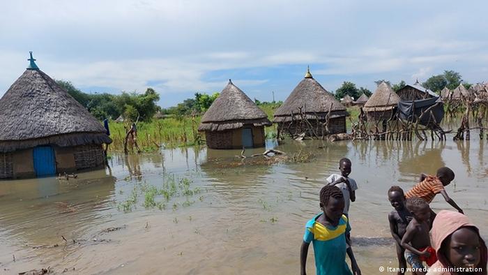 A group of children near huts submerged in water