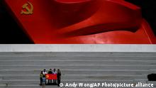 Visitors holding a Communist Party flag pose for a photo near a sculpture of the Chinese Communist Party flag at the Museum of the Communist Party of China, in Beijing, Wednesday, Aug. 31, 2022. China says a key congress of the ruling Communist Party at which leader Xi Jinping is expected to be granted a third five-year term will open on Oct. 16. (AP Photo/Andy Wong)