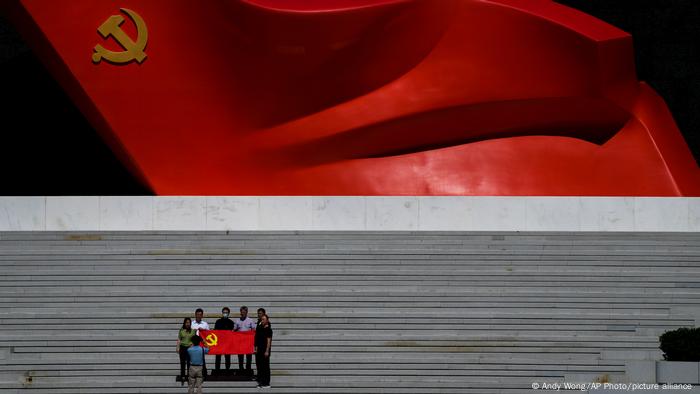 A group of people hold a Chinese flag in front of the Museum of the Communist Part of China