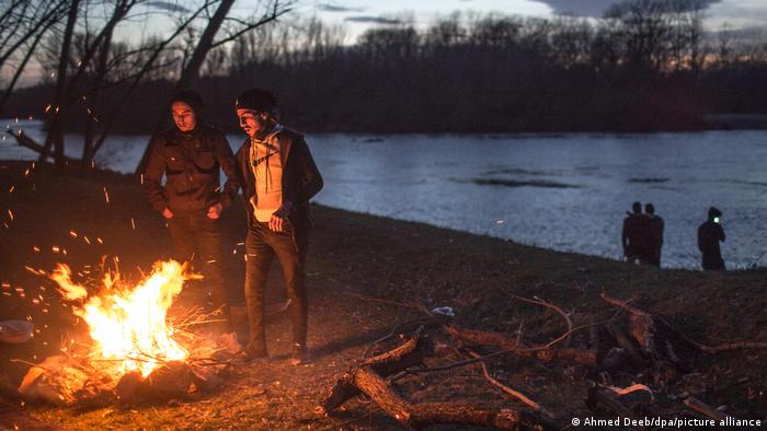 Flüchtlinge wärmen sich an einem Feuer am Ufer des Grenzflusses Evros im März 2022