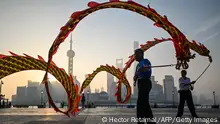 Men twirl dragon streamers on the Bund promenade along the Huangpu River during sunrise in Shanghai on September 7, 2022. (Photo by Hector RETAMAL / AFP) (Photo by HECTOR RETAMAL/AFP via Getty Images)