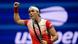 Tennis star Ons Jabeur raises her right fist, holding a tennis racket in her left hand. Tennis star Ons Jabeur raises her right fist, holding a tennis racket in her left hand.