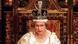 Queen Elizabeth II. mit Krone auf dem Kopf und in einem prächtig verzierten Holzstuhl im Parlament in London. Queen Elizabeth II. mit Krone auf dem Kopf und in einem prächtig verzierten Holzstuhl im Parlament in London.
