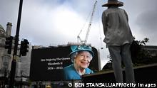 TOPSHOT - A person looks at a huge picture of Britain's Queen Elizabeth II displayed at Piccadilly Circus, in central London, on September 9, 2022, a day after Queen Elizabeth II died at the age of 96. - Queen Elizabeth II, the longest-serving monarch in British history and an icon instantly recognisable to billions of people around the world, died at her Scottish Highland retreat on September 8. (Photo by Ben Stansall / AFP) (Photo by BEN STANSALL/AFP via Getty Images)