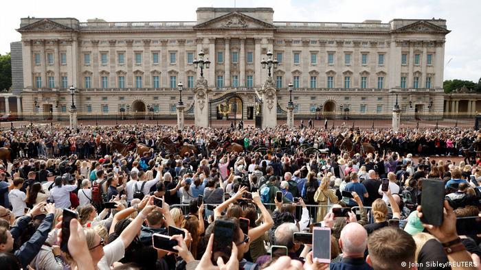 Crowds hold up their mobiles to take photos and videos of members of the King's Troop in front of Buckingham Palace