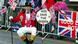 A royal well-wisher sits as crowd awaits the royals with a sign 'God save the queen' A royal well-wisher sits as crowd awaits the royals with a sign 'God save the queen'
