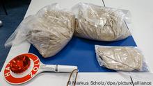 09.08.2018, Hamburg: Knapp 12 Kilogramm beschlagnahmtes Heroin im Schwarzmarktwert von ca. 600.000 Euro und eine Signalkelle mit der Aufschrift «Halt Zoll» liegen auf einem Tisch des Zollfahndungsamts Hamburg. Foto: Markus Scholz/dpa +++ dpa-Bildfunk +++