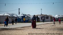 Women with children walk at Camp Roj, where relatives of people suspected of belonging to the Islamic State (IS) group are held, in the countryside near al-Malikiyah (Derik) in Syria's northeastern Hasakah province, on March 28, 2021. - Roj, one of two Kurdish-run displacement camps housing foreign family members of suspected IS fighters, is smaller and better guarded than its overcrowded counterpart Al-Hol, which has been rocked by assassinations and breakout attempts in recent months. (Photo by Delil SOULEIMAN / AFP) (Photo by DELIL SOULEIMAN/AFP via Getty Images)