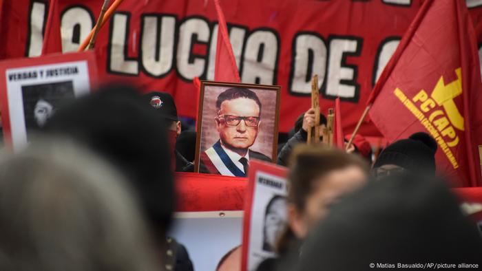 Foto de personas que participan en la conmemoración con una imagen de Salvador Allende en Chile.
