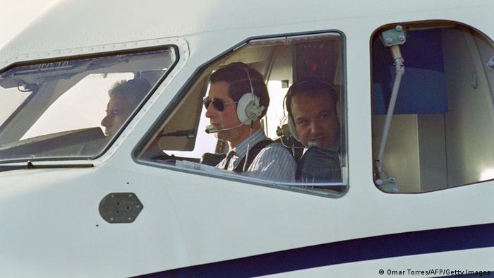 King Charles bestuurt een vliegtuig met twee andere passagiers.