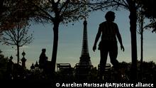 A woman walks in the Jardin des Tuileries, in front of the Eiffel Tower in Paris, France, Tuesday, Aug. 23, 2022. (AP Photo/Aurelien Morissard)