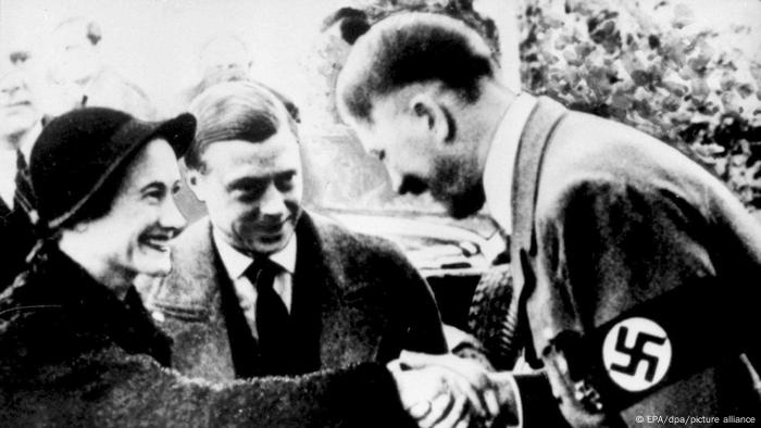 Herzog von Windsor und Ehefrau besuchen Hitler 1937, die Frau schüttelt lächelnd Hitlers Hand, der Mann steht lächelnd daneben.