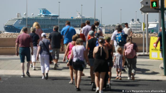 Az emberek sétálnak egy tengerjáró hajó felé Palma kikötőjében, Mallorcán