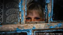 TOPSHOT - Antonina, 9, looks through a shrapnel-broken window after an online lesson on the first school day at her home in the village of Pokrovske, on September 1, 2022, amid Russian invasion of Ukraine. - In Pokrovske, a tiny village of 24 people in the Mykolayev region of southern Ukraine, nine-year-old Antonina Sidorenko started school to the steady sound of cannons in this town near the front line. (Photo by Dimitar DILKOFF / AFP) (Photo by DIMITAR DILKOFF/AFP via Getty Images)