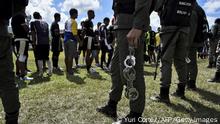 A member of the Bolivarian National Guard holds handcuffs after taking them off from inmates of a rugby team during the Penitentiary Rugby Tournament organized by the Santa Teresa Foundation, at the sports field Hacienda Santa Teresa in La Victoria, Aragua State, Venezuela, on December 1, 2018. - Twelve penitentiary centres from across the country are taking part in the Alcatraz Project, which aims to rehabilitate and reintegrate inmates into society and stop violence in the Venezuelan prisons. (Photo by Yuri CORTEZ / AFP) (Photo credit should read YURI CORTEZ/AFP via Getty Images)