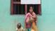 Mulher em zona rural com um bebê no colo e dando a mão para uma criança