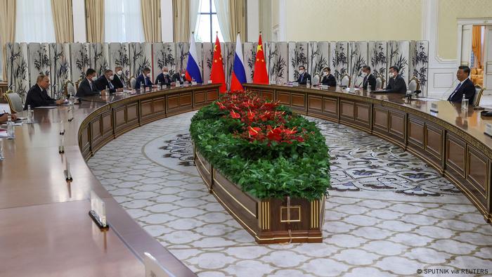 Putin y Xi sentados en una gran mesa de negociación junto a sus repectivas delegaciones.