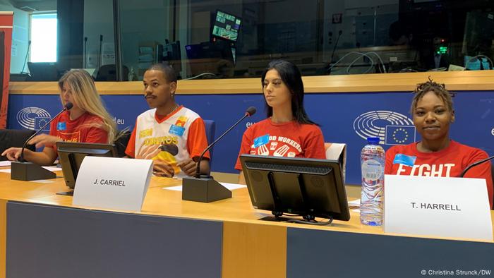 Young people at a speaker's desk in the European Parliament, all wearing red T-shirts