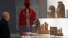Ein Mann betrachtet zu Beginn einer Pressekonferenz vor der letzten Teileröffnung des Humboldt Forums die sogenannten Benin Bronzen. Die Sammlungspräsentationen des Ethnologischen Museums und des Museums für Asiatische Kunst der Staatlichen Museen zu Berlin sind mit rund 20 000 Exponaten auf 16 000 Quadratmetern dann vollständig zu sehen. +++ dpa-Bildfunk +++