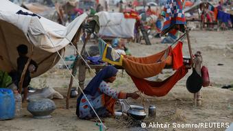 Un campamento en Pakistán, donde una mujer cocina delante de una carpa improvisada.