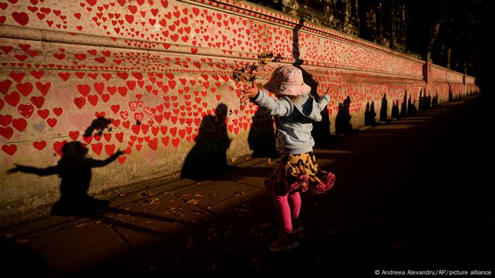 Ellie, de dos años y medio, lanza hojas al aire sobre un muro conmemorativo de la pandemia de coronavirus, mientras miles de personas hacen fila para rendir homenaje a la reina Isabel II, en Londres, Inglaterra. La capilla ardiente en el Westminster Hall, ubicado en el Parlamento británico, durará cuatro días hasta el funeral y entierro de la monarca el 19 de septiembre.