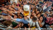 Young people reach out for free beer in one of the beer tents on the opening day of the 187th Oktoberfest beer festival in Munich, Germany, Saturday, Sept. 17, 2022. Oktoberfest is back in Germany after two years of pandemic cancellations, the same bicep-challenging beer mugs, fat-dripping pork knuckles, pretzels the size of dinner plates, men in leather shorts and women in cleavage-baring traditional dresses. (AP Photo/Michael Probst)