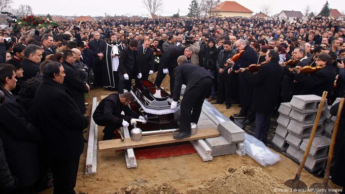 Hundreds of mourners in black at a funeral in Tatarszentgyörgy, Hungary, watch as a coffin is lowered into the ground Hundreds of mourners in black at a funeral in Tatarszentgyörgy, Hungary, watch as a coffin is lowered into the ground