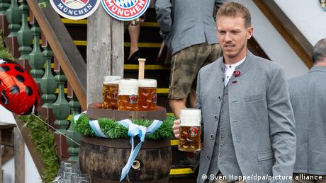 Julian Nagelsmann carries a beer while dressed in traditional Bavarian dress at Oktoberfest