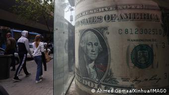 Άνθρωποι περπατούν δίπλα από γραφείο συναλλάγματος στο Κάιρο.