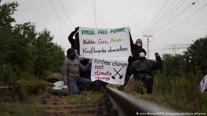 Protesters hold up to placards on rail lines close to a coal power plant in Brandenburg, eastern Germany, 19 September, 2022.