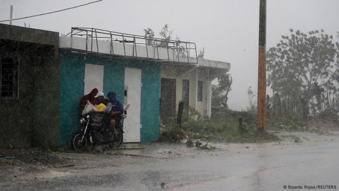 Dos hombres protegiéndose de los intensos vientos del Huracán Fiona. 