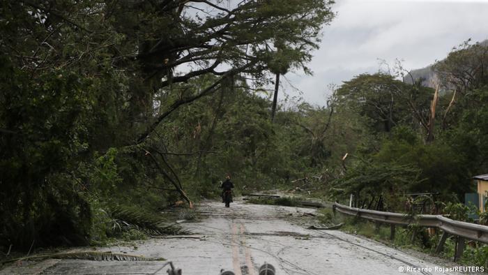 A man on a motorcycle rides past fallen power lines in the aftermath of Hurricane Fiona in Higuey, Dominican Republic