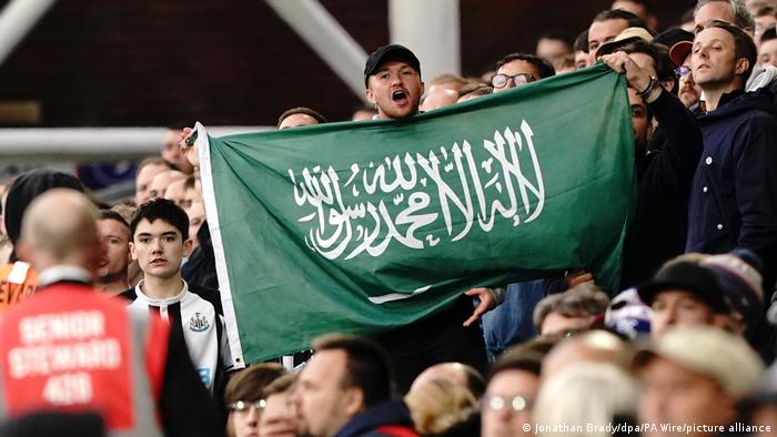 Newcastle fan holds a Saudi Arabia flag