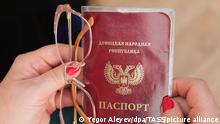 1.7.2022, Donetsk, Ukrine, DIESES FOTO WIRD VON DER RUSSISCHEN STAATSAGENTUR TASS ZUR VERFÜGUNG GESTELLT. [DONETSK, DONETSK PEOPLE'S REPUBLIC - JULY 4, 2022: A local woman holds a Russian passport in the migration service office of the DPR Interior Ministry. The republic's citizens were able to receive Russian passports earlier, but for this they had to travel to Russia. Centres for applying documents and issuing passports are planned to open in Khartsyzsk, Yenakiyevo, and Mangush in July. On 24 April 2019, Russia's President Vladimir Putin signed a decree to simplify the procedure for obtaining Russian passports for residents of the Donetsk People's Republic and Lugansk People's Republic. Yegor Aleyev/TASS]