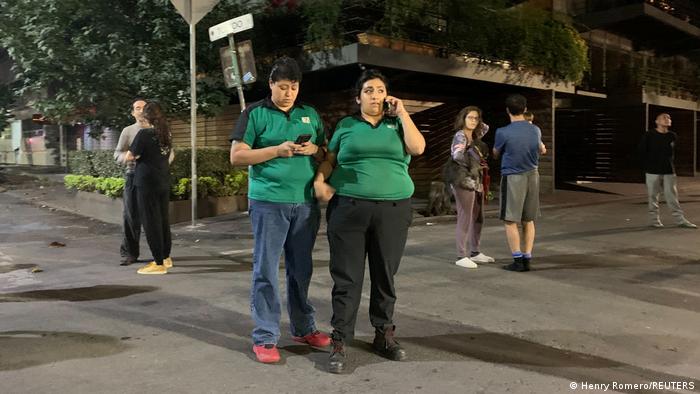 People wait outside their homes after a tremor was felt in Mexico City
