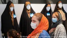 An Iranian family walk past mannequins that are decorated with traditional covering while visiting of the 11th Fajr International Fashion and Clothing Festival at Tehran's Milad tower Cultural and Recreational complex on July 11, 2022. In Iran's official calendar, July 12 is named Hijab and Chastity Day by the Iranian Government. (Photo by Morteza Nikoubazl/NurPhoto)