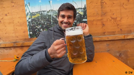 Ein Mann sitzt an einem Biertisch und trinkt Bier aus einem großen Glas (Quelle: DW) 