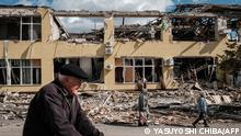 People walk past a destroyed building in Kupiansk, Kharkiv region, on September 19, 2022, amid the Russian invasion of Ukraine. - In the northeastern town of Kupiansk, which was recaptured by Ukrainian forces, clashes continued with the Russian army entrenched on the eastern side of the Oskil river. (Photo by Yasuyoshi CHIBA / AFP)