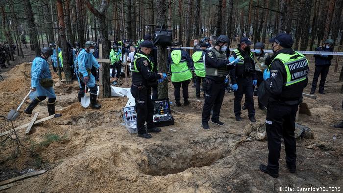 Police and experts work at a place of mass burial during exhumation in the town of Izium
