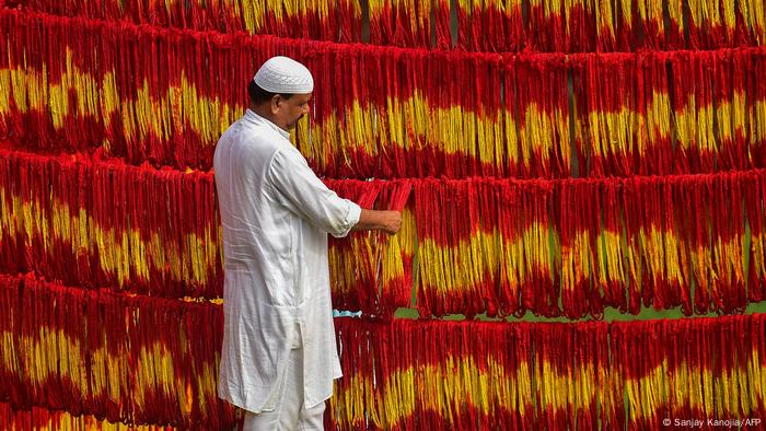 El dueño de un taller revisa los llamados hilos kalawa que fueron recién teñidos. Estos son hilos tradicionales sagrados de color amarillo y anaranjado que se usan en los rituales hindúes, antes del festival Navratri, en el pueblo de Lalgopalganj, a unos 45 km de Allahabad, India.