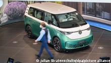 Ein Mitarbeiter läuft neben einem Volkswagen Elektrobus ID.Buzz in der Autostadt am Volkswagen Stammwerk. Die Hauptversammlung der Volkswagen AG findet am 12. Mai statt.