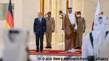 In this photo released by Qatar News Agency, German Chancellor Olaf Scholz, left, is received by the Emir of Qatar, Sheikh Tamim bin Hamad Al Thani, in Doha, Qatar, Sunday, Sept. 25, 2022. (Qatar News Agency via AP)