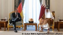 In this photo released by Qatar News Agency, German Chancellor Olaf Scholz, left, talks with the Emir of Qatar, Sheikh Tamim bin Hamad Al Thani, in Doha, Qatar, Sunday, Sept. 25, 2022. (Qatar News Agency via AP)